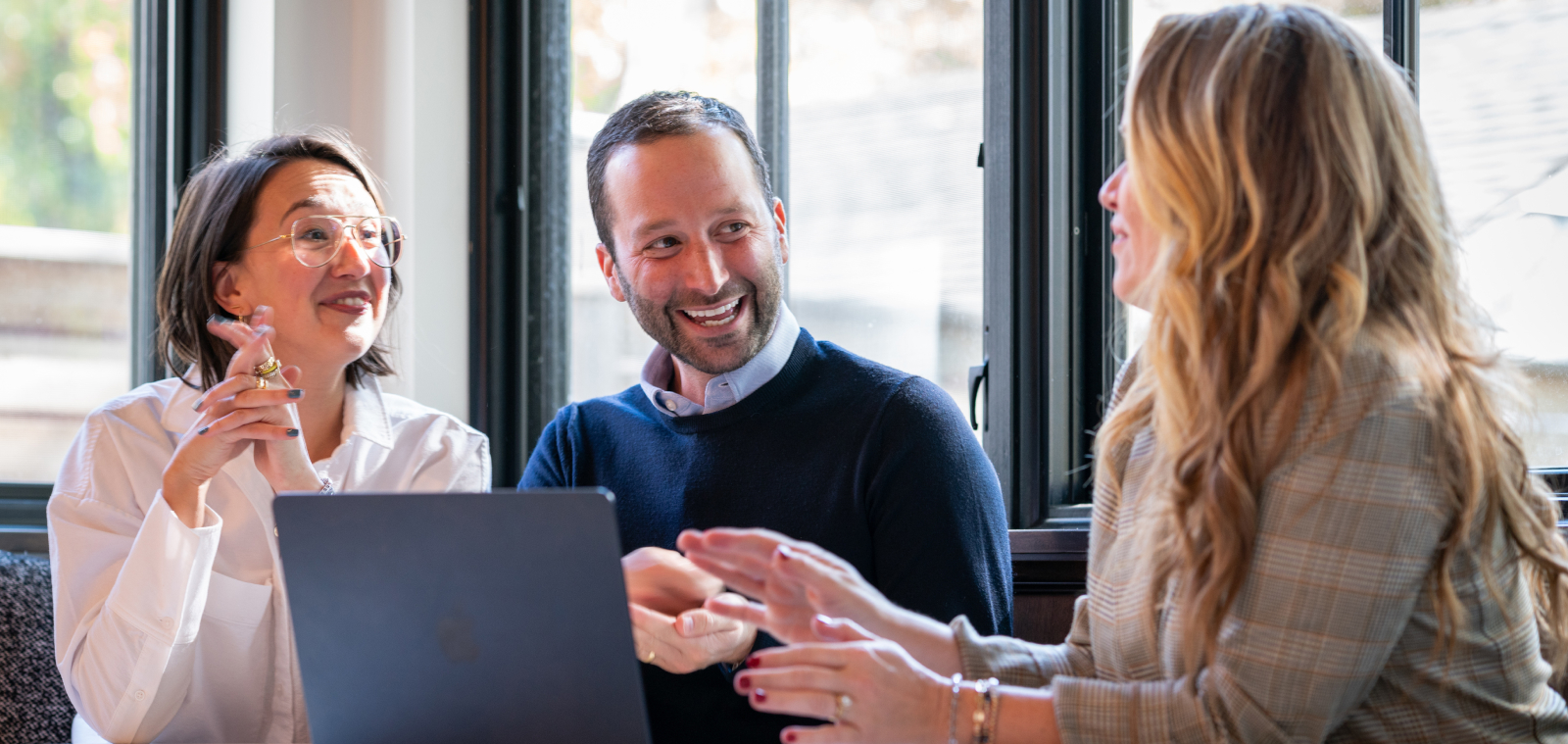 Three people having a discussion around a laptop
